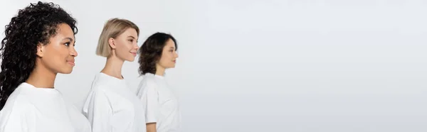 Positive african american woman standing near blurred friends isolated on grey, banner — Stock Photo