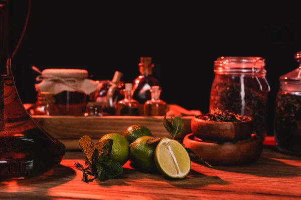 Limes in der Nähe von Wasserpfeife und trockenem Tee auf hölzerner Oberfläche isoliert auf schwarz — Stockfoto