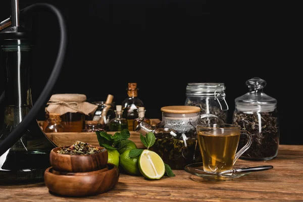 Dry tea, limes near hookah on wooden surface isolated on black — Stock Photo