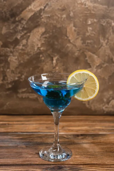 Blue cocktail in glass on wooden surface on textured stone background — Stock Photo