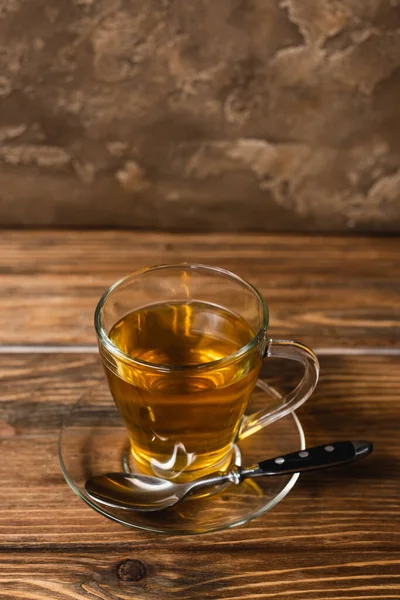 High angle view of cup of tea on saucer on wooden surface on textured stone background — Stock Photo