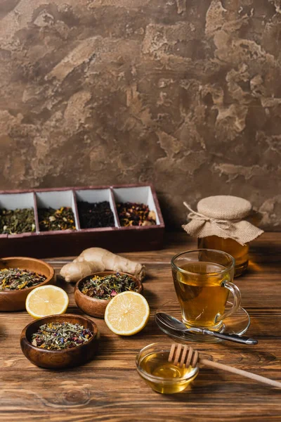 Tea, lemon and jar with hone on wooden surface on textured stone background — Stock Photo