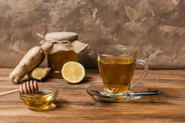 Tea and honey in bowl on wooden surface on textured stone background — Stock Photo