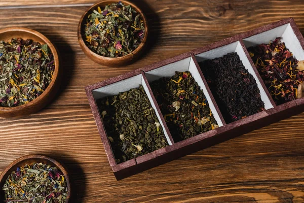 Top view of dry tea in box and bowls on wooden surface — Stock Photo