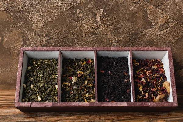Vue du dessus du thé sec en boîte sur une surface en bois sur fond de pierre texturée — Photo de stock