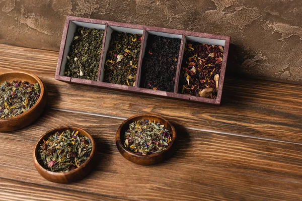 Vista superior del té en caja y cuencos en superficie de madera sobre fondo de piedra texturizada - foto de stock