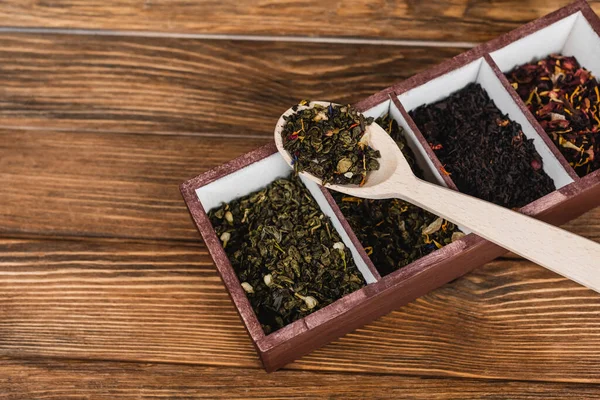 Top view of dry tea on spoon and box on wooden surface — Stock Photo