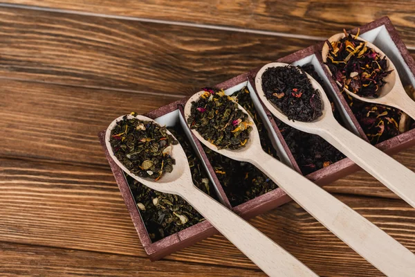 Vista dall'alto del tè in cucchiai e scatola sulla superficie di legno — Foto stock