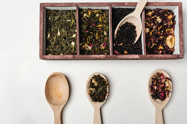 Vista superior del té seco en caja y cucharas de madera sobre fondo blanco — Stock Photo