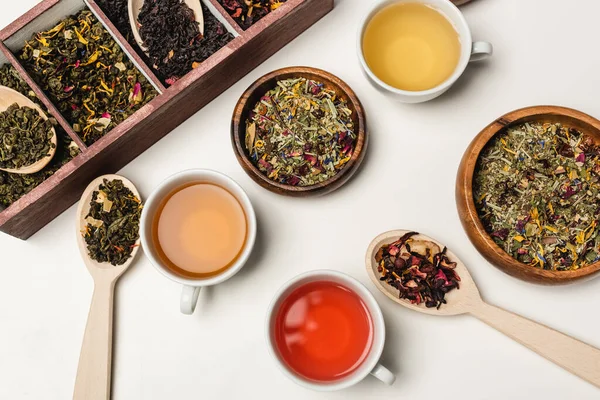 Top view of cups of tea near spoons and wooden bowls on white background — Stock Photo