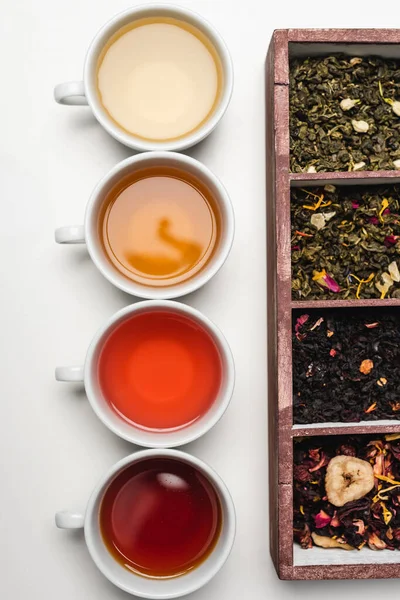 Draufsicht auf Tassen Tee und Holzkiste auf weißem Hintergrund — Stockfoto