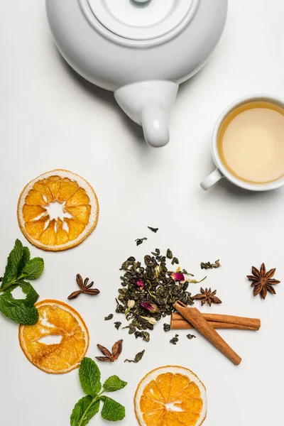 Draufsicht auf Teekanne in der Nähe von trockenem Tee, Gewürzen und Minze auf weißem Hintergrund — Stockfoto