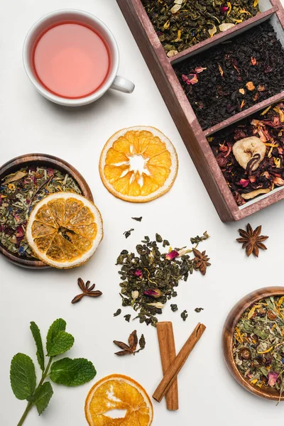 Vista superior del té seco cerca de la taza, especias y menta sobre fondo blanco — Stock Photo