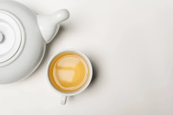 Vista superior de la taza de té y tetera sobre fondo blanco - foto de stock