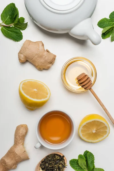 Draufsicht auf eine Tasse Tee in der Nähe von Ingwer und Minze auf weißem Hintergrund — Stockfoto