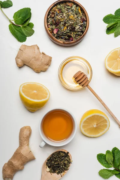 Vue du dessus du miel, tasse de thé et menthe sur fond blanc — Photo de stock