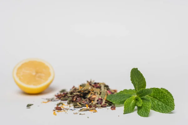Nahaufnahme von Minze in der Nähe von trockenem Tee und verschwommener Zitrone auf weißem Hintergrund — Stockfoto