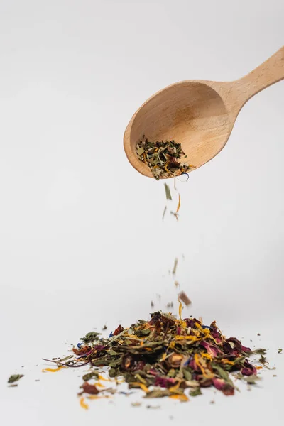 Cuchara de madera cerca del té seco sobre fondo blanco - foto de stock