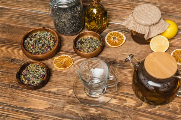 Tazza vicino a tè, miele e ciotole sulla superficie di legno — Foto stock