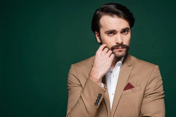 Young man with mustache looking at camera on dark green — Stock Photo