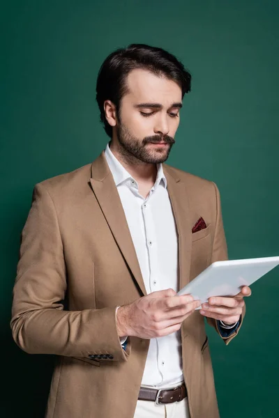 Jeune homme avec moustache tenant tablette numérique sur vert foncé — Photo de stock