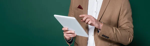 Vista recortada de hombre joven utilizando tableta digital en verde oscuro, bandera - foto de stock