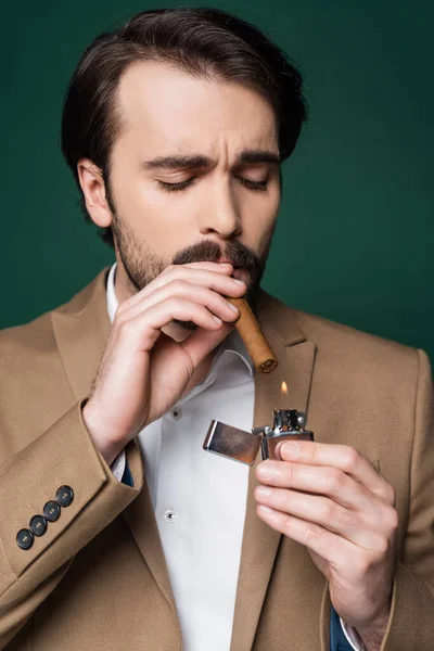 Portrait of man with mustache holding cigar near lighter on dark green — Stock Photo