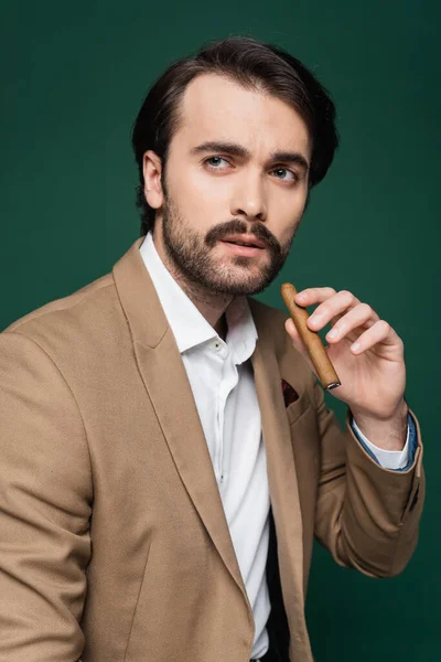 Homme avec moustache tenant cigare et regardant loin sur vert foncé — Photo de stock