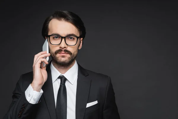 Homme d'affaires avec moustache parlant sur smartphone sur gris foncé — Photo de stock