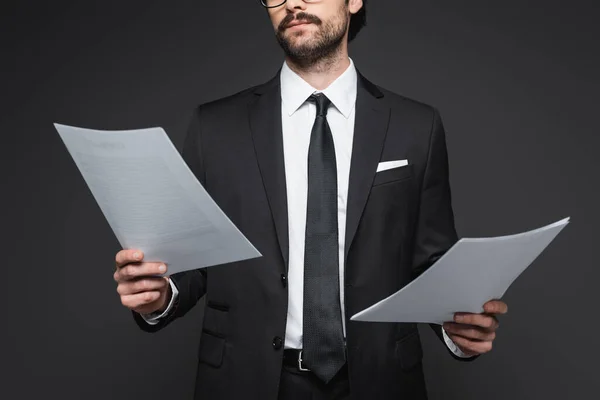 Vue recadrée d'un homme d'affaires avec moustache tenant des documents sur gris foncé — Photo de stock