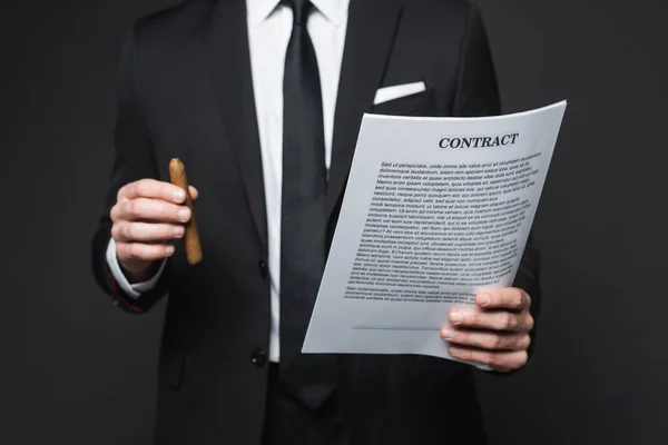 Cropped view of businessman in suit holding cigar and contract on dark grey — Stock Photo