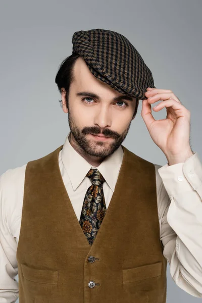Portrait of man with mustache adjusting vintage hat isolated on grey — Stock Photo