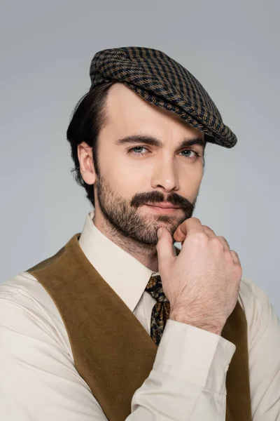 Portrait of pensive man with mustache and retro clothing touching chin isolated on grey — Stock Photo