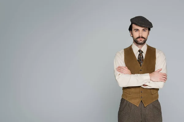 Homme avec moustache et vêtements rétro debout avec bras croisés isolés sur gris — Photo de stock