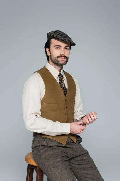 Man with mustache and retro style clothing sitting on chair on grey — Stock Photo