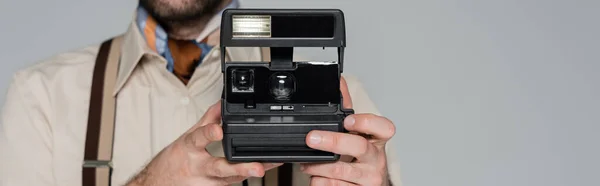 Cropped view of man retro style clothing and hat holding vintage camera isolated on grey, banner — Stock Photo