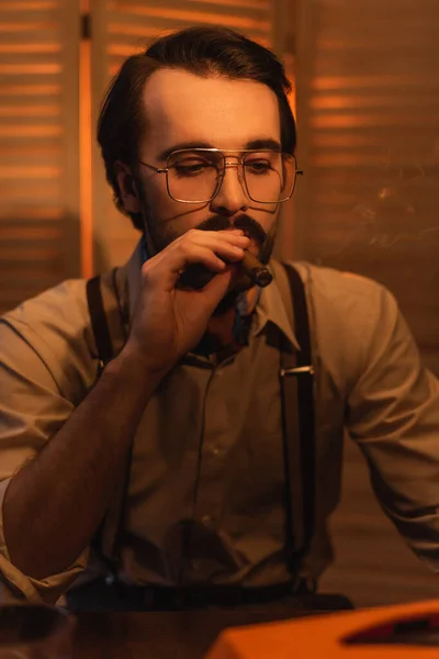 Mann mit Schnurrbart in Brille raucht Zigarre neben verschwommenem Klappbildschirm — Stockfoto