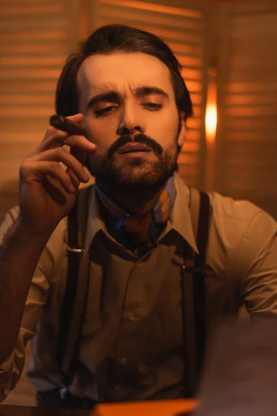 Writer holding cigar and looking at typewriter machine against blurred folding screen — Stock Photo