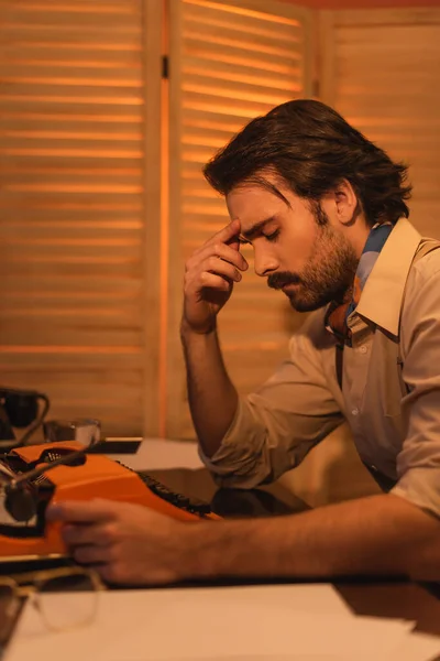 Side view of pensive writer thinking near typewriter machine — Stock Photo
