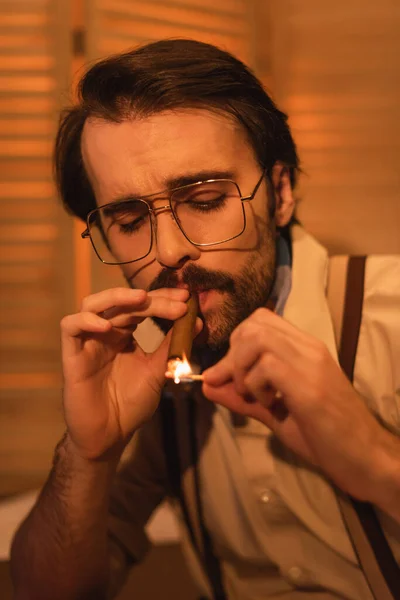 Homme avec moustache et lunettes tenant match près du cigare — Photo de stock