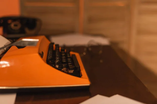 Antique and orange typewriter machine near papers on desk — Stock Photo