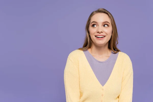 Lächelnd und junge Frau, die isoliert auf violett wegschaut — Stockfoto