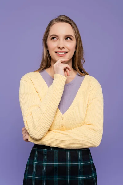 Souriant et jeune femme regardant loin et pensant isolé sur violet — Photo de stock