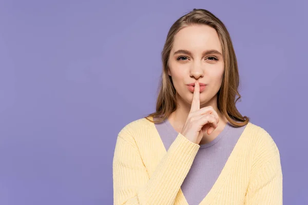 Jeune femme regardant la caméra et montrant signe de silence isolé sur violet — Photo de stock