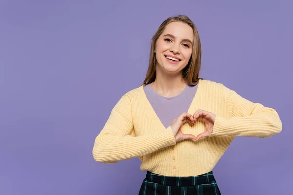 Freudige junge Frau zeigt Herzzeichen mit Händen, die auf violett isoliert sind — Stockfoto