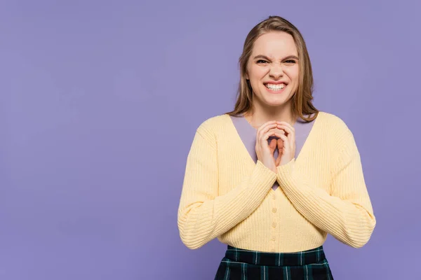 Astuta joven sonriendo y haciendo gestos aislados en púrpura - foto de stock