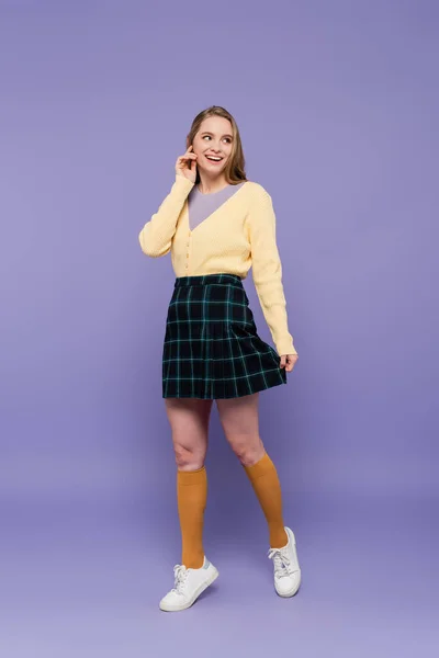 Full length of young woman in skirt smiling on purple — Stock Photo