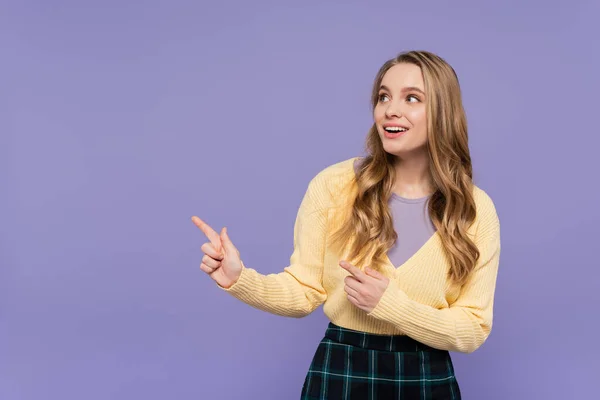 Freudige junge Frau zeigt mit Fingern auf lila — Stockfoto