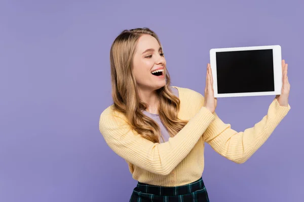 Amazed young woman holding digital tablet with blank screen isolated on purple — Stock Photo