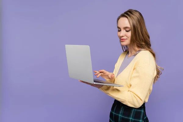 Веселий студент використовує ноутбук ізольований на фіолетовому — стокове фото